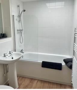 ein Badezimmer mit einer weißen Badewanne und einem Waschbecken in der Unterkunft The Coach House in Welwyn Garden City