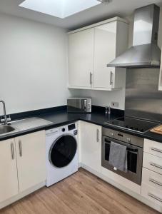 uma cozinha com armários brancos e uma máquina de lavar louça em The Coach House em Welwyn Garden City