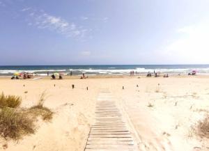 a sandy beach with people on the beach at Apartamento en duplex El Riuet in Oliva