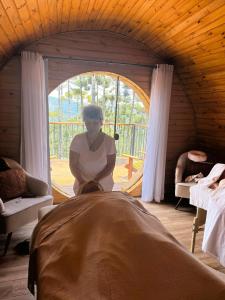 モンテ・ヴェルデにあるPousada Villa Barrilのベッド1台の部屋に座る女性