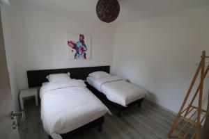dwa łóżka w pokoju z białą pościelą w obiekcie Gîte Le Scarabée w mieście Saint-Dié