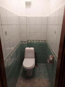 a bathroom with a toilet in a green tiled room at PēterGailis17 in Ventspils