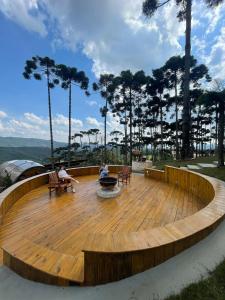 a large wooden deck with two people sitting on benches at Pousada Villa Barril in Monte Verde