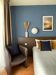 um quarto com uma cadeira, uma cama e paredes azuis em Résidence Les Baladines em Thonon-les-Bains