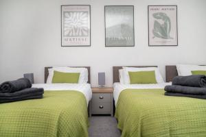 a bedroom with two beds with green sheets and posters at Spacious Home In The Heart of West Yorkshire in Brighouse