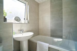 uma casa de banho com um lavatório e uma banheira em Woodside Apartment em Coatbridge