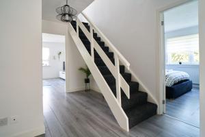 Habitación blanca con escalera y dormitorio en Woodside Apartment, en Coatbridge