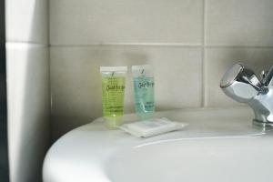 lavabo en el baño con 2 botellas de pasta de dientes y una cuchilla de afeitar en Woodside Apartment en Coatbridge