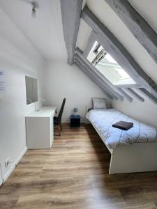 Cette chambre mansardée comprend un lit et un bureau. dans l'établissement Le Saint Julien - 5 chambres, spacieux et calme, à Rouen