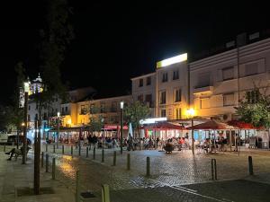 uma rua da cidade à noite com pessoas sentadas em mesas em Link Alcácer em Alcácer do Sal