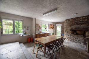 a kitchen with a wooden table and a stone fireplace at Exclusiva Casa Rural Mariano con acceso directo al rio in Baralla