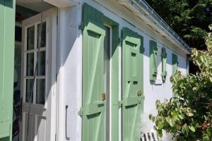 a green and white house with green shutters at Jolie maison, 500 m de la plage, grand jardin in Les Portes