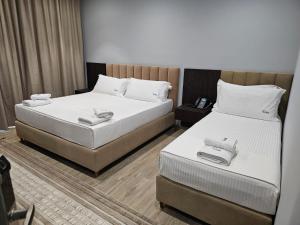 2 camas en una habitación de hotel con sábanas blancas en KAAN Hotel, en Vlorë