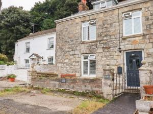 an old stone house with a black door at Still Waters in St Austell