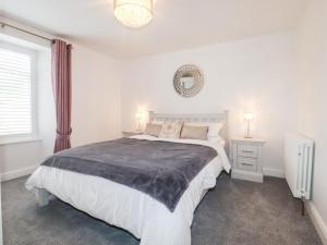 a white bedroom with a large bed and a mirror at Still Waters in St Austell