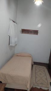 a bed in a room with a white wall at Pouso dos Sinos in Ouro Preto