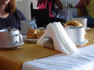 einen Tisch mit Tassen Kaffee und Gebäck darauf in der Unterkunft Condor in Mina Clavero
