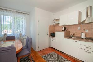 a kitchen with white cabinets and a table and a dining room at Apartman Plitvice Happy Home in Plitvička Jezera