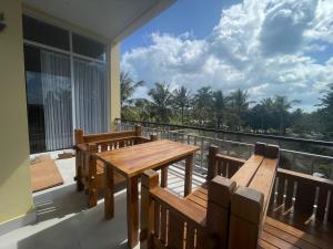 balcón con mesa de madera y bancos en Kelingking Hostel en Klungkung