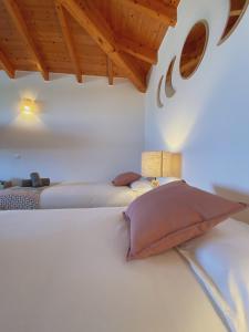two beds in a room with wooden ceilings at The Lighthouse Hostel Arrifana in Aljezur