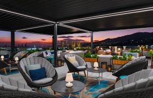 un patio all'ultimo piano con sedie, tavoli e un tramonto di The BRIX Autograph Collection a Port-of-Spain
