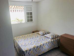 um pequeno quarto com uma cama e uma janela em Chez Nouny em Le Marin