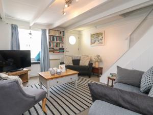 a living room with a couch and a tv at Kerbenetty Harbour Cottage in Portloe