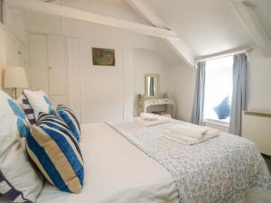 a white bed with two towels on top of it at Kerbenetty Harbour Cottage in Portloe