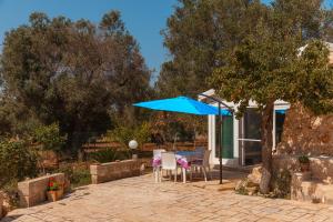 a patio with a blue umbrella and chairs at Trullo Tarantini con piscina privata in Latiano