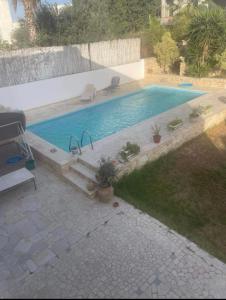 a swimming pool in a yard next to a house at La maison les pins Chambre d'hote chez l'habitant in La Marsa