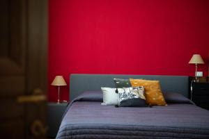 Un dormitorio con una pared roja y una cama con almohadas en Mimma bed&flavour, en Narni