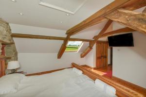 a bedroom with a bed and a flat screen tv at Haye Barton Farm in Liskeard