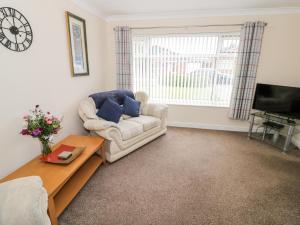 a living room with a couch and a tv at Lynsted Lodge in Ashby de la Zouch