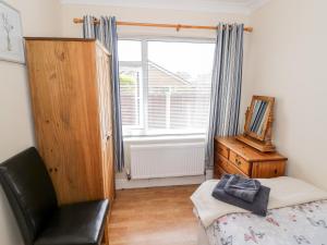 a bedroom with a bed and a chair and a window at Lynsted Lodge in Ashby de la Zouch