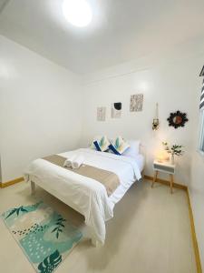 a white bedroom with a bed and a table at Sunset Paradise Moalboal in Moalboal