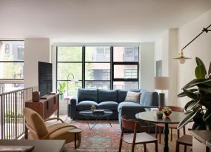 a living room with a blue couch and tables and chairs at Roost Baltimore in Baltimore