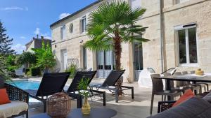 een patio met een tafel en stoelen en een palmboom bij L'Angély - Chambres d'Hôtes in Niort