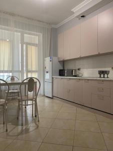 cocina con armarios blancos, mesa y sillas en Красивая уютная двухкомнатная квартира в Экспо, en Taldykolʼ