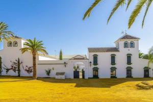 een groot wit gebouw met een palmboom ervoor bij Cortijo Pavia in Écija