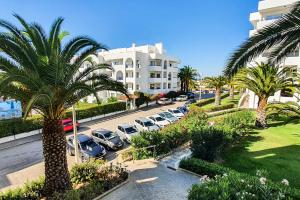 a row of parked cars in a parking lot with palm trees at Be my Guest in Armação de Pêra
