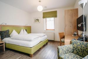 a hotel room with two beds and a chair at Gästehaus Thomahan in Friesach