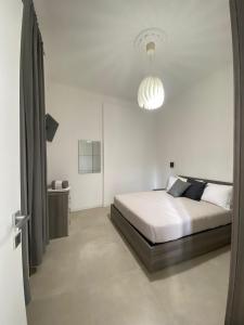a white bedroom with a bed and a chandelier at San Martino Rooms Third Floor No Lift in La Spezia