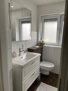 La salle de bains blanche est pourvue d'un lavabo et de toilettes. dans l'établissement Wohnen im Reihenhaus auf Zeit in Lübeck, à Lübeck
