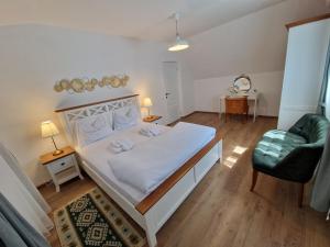 a bedroom with a white bed and a chair at Maximus Apartments in Sighişoara