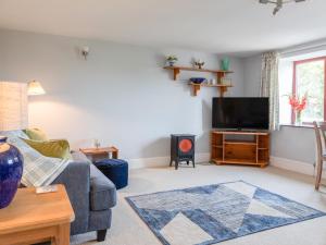 a living room with a couch and a tv at Honeysuckle Cottage in Kingsbridge