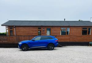 a blue car parked in front of a house at Clochnaben lodge, castle wood, strachan ab31 6NQ in Strachan