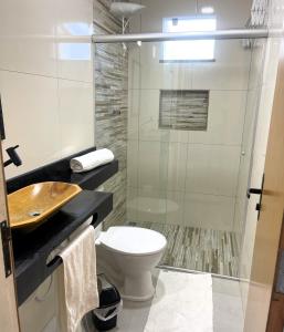 a bathroom with a toilet and a glass shower at Atenas - Lofts com Cozinha - Próximo Aeroporto e Rodoviária in Porto Seguro +66 photos