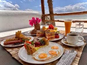 uma mesa com pratos de comida para o pequeno-almoço e uma chávena de café em Stone Resort em Kiwengwa