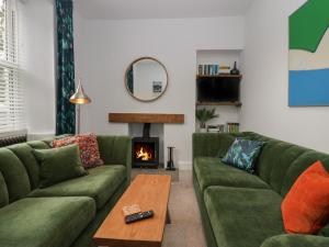 a living room with green couches and a fireplace at Rose Cottage in Ambleside