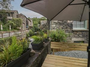 a wooden bench with an umbrella in a garden at Rose Cottage in Ambleside